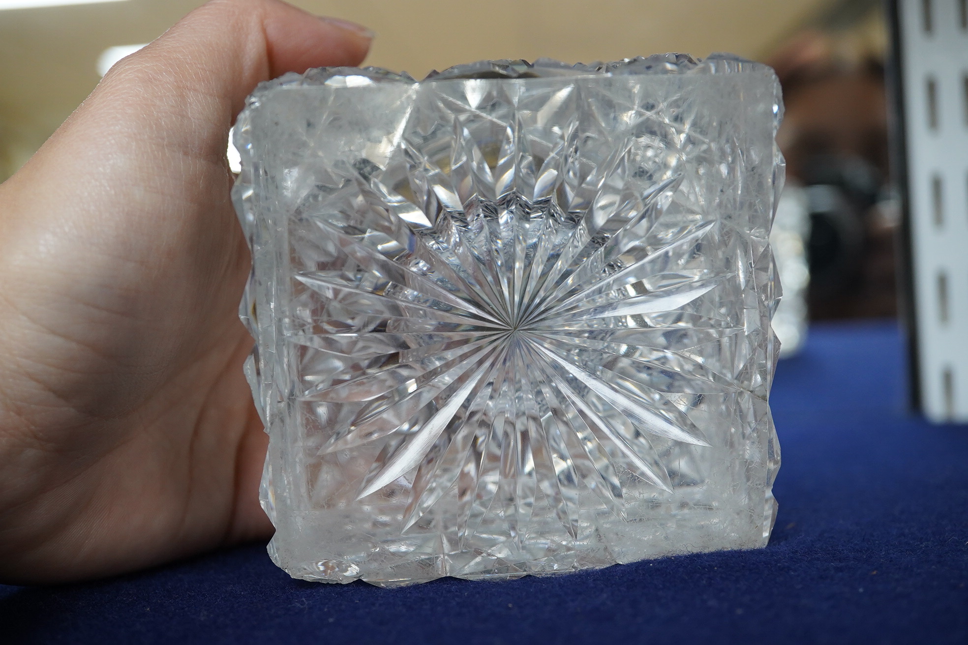 A large square glass inkwell, heavily cut with star cut base and octagonally cut top with enamelled brass hinged cover, 8cm wide. Condition - fair, some chipping